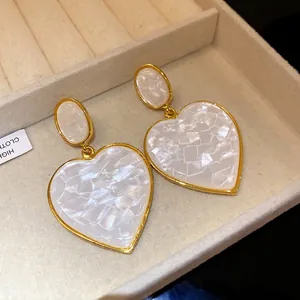 Elegant vintage heart-shaped drop earrings with white resin inlay and gold-tone finish