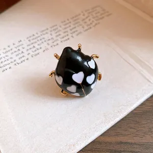 Macro view of black enamel ladybug ring with white heart dots and gold plating finish