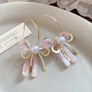 Detail view of pink acetate bow earrings with pearl center on a vintage ceramic plate