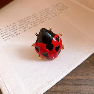 Detail shot of an enamel ladybug ring with red finish and black heart-shaped spots.