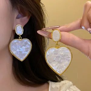 Close-up of vintage resin heart drop earrings with white marbled texture and gold trim