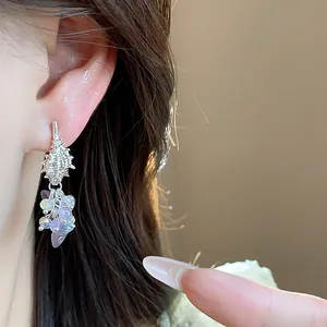 Close-up detail of conch tassel earrings with iridescent purple beads worn on ear
