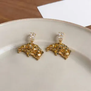 Detail view of gold French style stud earrings with rectangular zircon drops