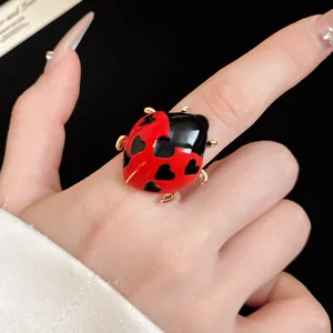 Close-up detail of a vibrant red and black enamel ladybug ring with heart patterns