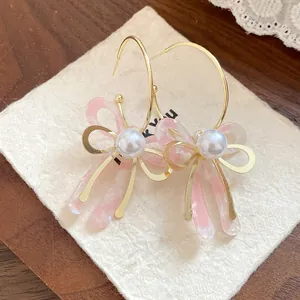 Macro view of sweet pink acetate bow-knot earrings with pearls and 925 silver needles
