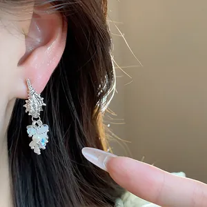 Close-up detail of silver conch tassel earrings with pearls and sparkling crystals on model