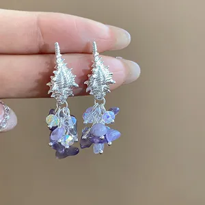 Close-up of silver-tone conch stud earrings with purple stone bead tassels