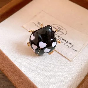 Macro view of ladybug enamel ring with heart-shaped patterns on a display tray