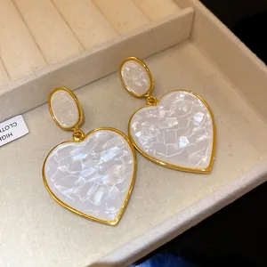 Macro detail of vintage-style marbled resin heart drop earrings with gold-tone frames
