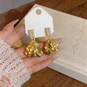 Close-up of elegant gold-toned earrings with zircon accents on a display card