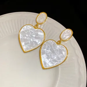 Detailed macro shot of vintage gold-rimmed heart-shaped earrings with resin inlay