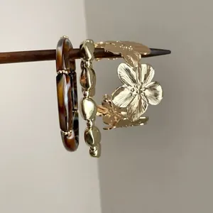 Detailed view of vintage flower and gold beaded bracelets with tortoiseshell bangle.