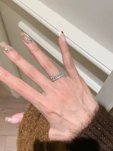 Nahaufnahme eines luxuriösen silbernen Zirkonia-Spitzenrings an einem dekorierten Finger