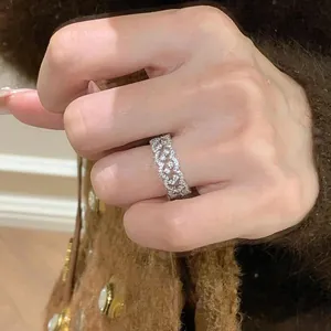 Nahaufnahme eines funkelnden Zirkonia-Spitzenrings mit Wellenmuster an der Hand