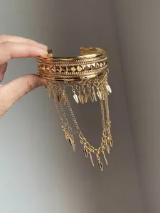 Detailed view of a gold cuff bracelet with geometric studs and long tassel charms