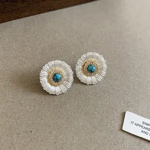 Detailed macro view of retro silver daisy stud earrings with turquoise center stone