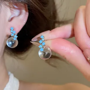 Close-up detail of vintage style blue zircon earrings with a clear glass bubble drop.