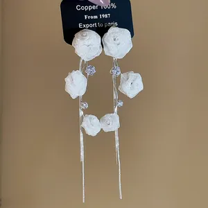 Close-up of elegant French mesh rose earrings with long silver tassels and crystals