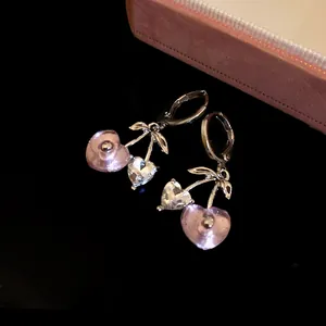 Close-up detail of heart-shaped cherry dangle earrings with pink resin and crystals.