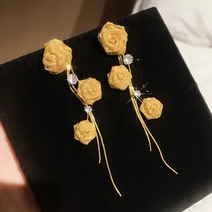 Detailed view of elegant gold mesh rose earrings with sparkling stones and long tassels.