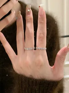 Nahaufnahme von eleganten Zirkon-Spitzenringen an einer Hand mit Wellenmuster-Details