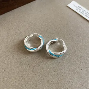 Close-up of vintage silver hollow hoop earrings with delicate blue bead accents for women