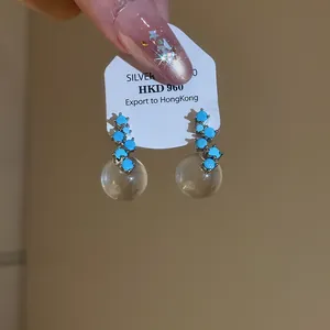 Close-up of vintage drop earrings with turquoise stones and clear glass balls.