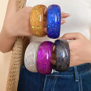 Close-up detail of colorful resin bangles featuring embedded star glitter and sequins.