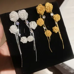 Detail of mesh rose tassel earrings with crystal accents in gold and silver