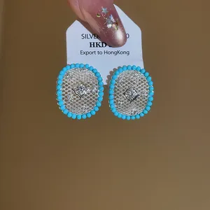 Close-up of elegant retro openwork earrings featuring turquoise beads and central zircon