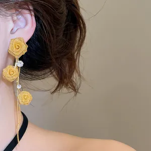 Close-up of elegant French style gold mesh rose tassel earrings worn on a female model