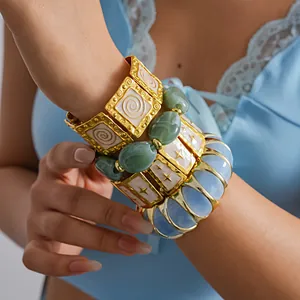Detail shot of stacked colorful metal bracelets with star pattern on a model's wrist