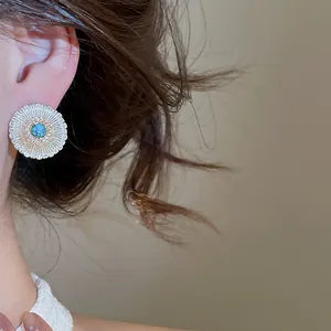 Detailed view of a vintage daisy zircon earring with turquoise center on model's ear