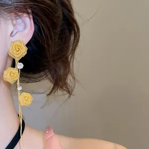 Detail of gold mesh rose tassel earrings with crystal accents on an Asian model
