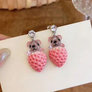 Primer plano de pendientes de oso fresa de resina con brillantes tachuelas de circonita.