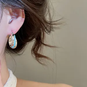 Close-up detail of a vintage textured silver hoop earring with blue beads worn on ear