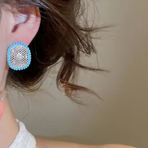 Close-up view of vintage style hollow mesh daisy stud earring with blue beaded border