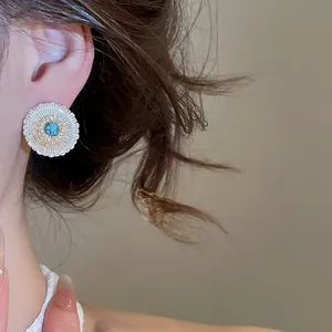 Close-up of vintage-style hollow daisy flower stud earring with turquoise center.