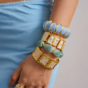 Close-up of layered bohemian gold-tone enamel bracelets with star and spiral patterns.