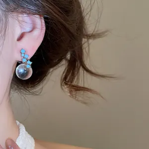 Detail view of a vintage style earring with blue turquoise stones and a clear bubble bead