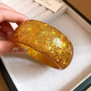 Detailed macro shot of a golden resin bangle with embedded star and snowflake glitter