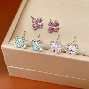 Detailed view of three pairs of zircon clover stud earrings in pink, blue, and white.