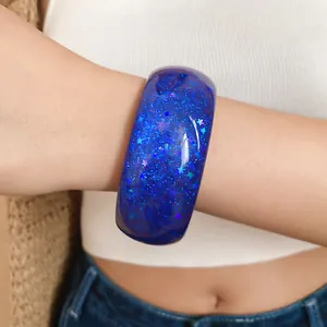 Detailed close-up showing a blue resin bangle bracelet with shining star glitter