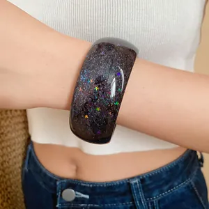 Close-up of resin bangle with sparkling stars and snowflakes on a female model's wrist