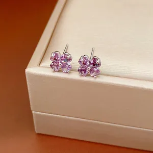 Close-up of purple zircon clover flower stud earrings on a beige gift box.