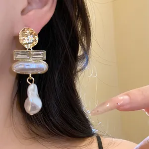 Close-up detail of vintage Baroque pearl earrings with gold accents worn by a model