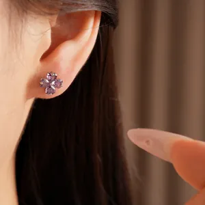 Detailed macro view showing a purple heart-shaped zircon clover stud earring worn on ear