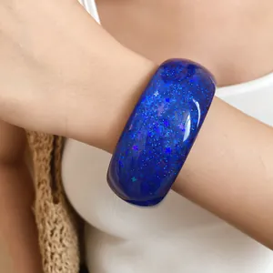 Macro detail of blue resin bangle featuring sparkling star glitter on woman's wrist