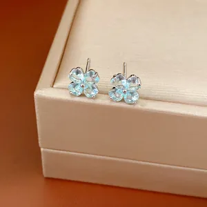 Detailed view of silver needle earrings with light blue zircon four-leaf clover design.
