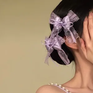 Dettaglio di un'elegante molletta per capelli con fiocco in pizzo viola.